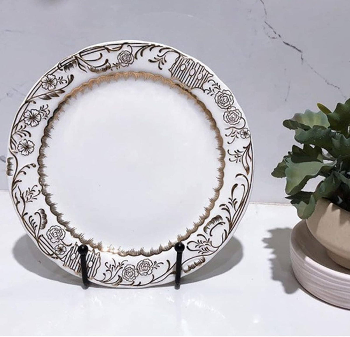 Black metal plate holder supporting a decorative round plate on the stand