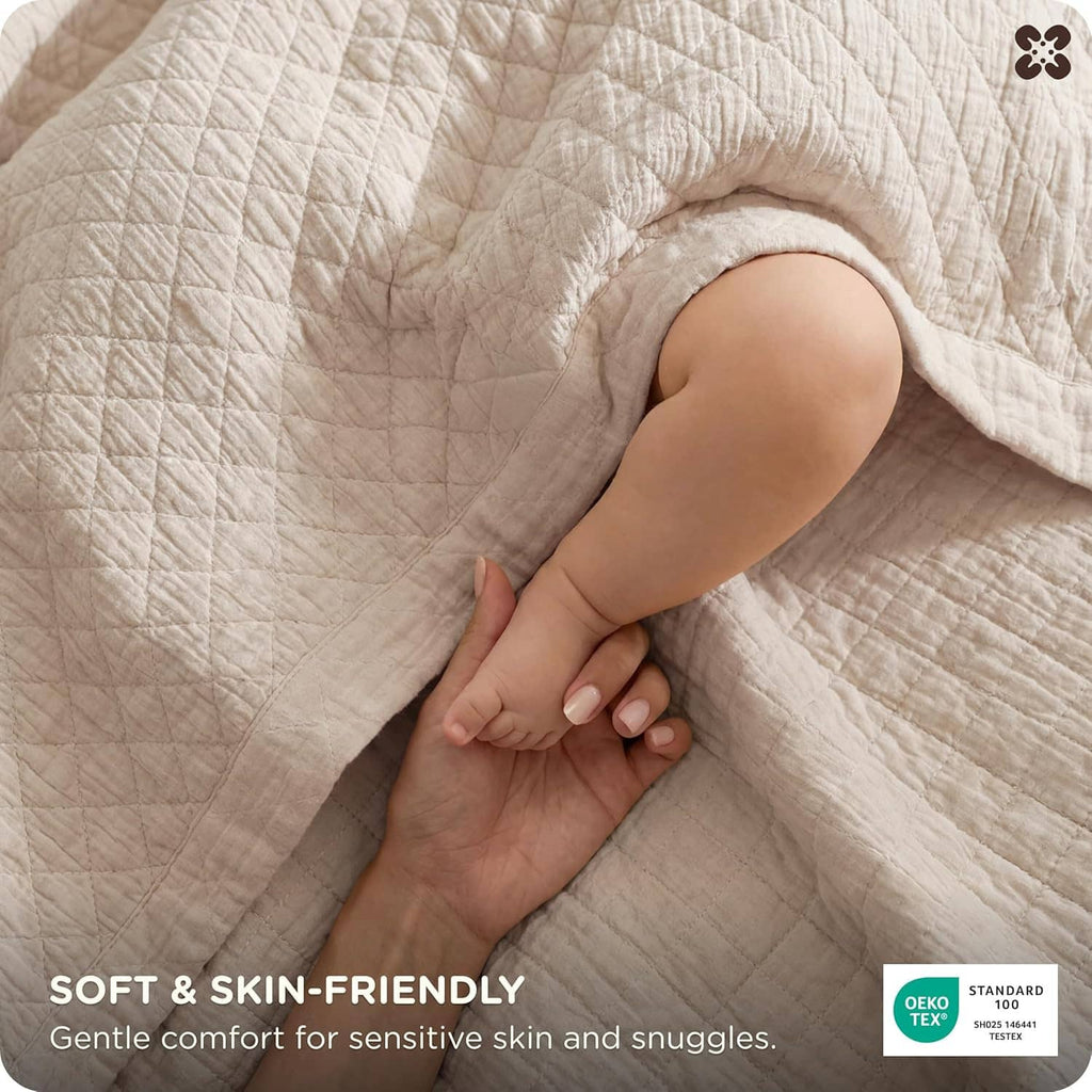 Cream cotton muslin blanket close-up with quilted diamond texture and smooth stitching