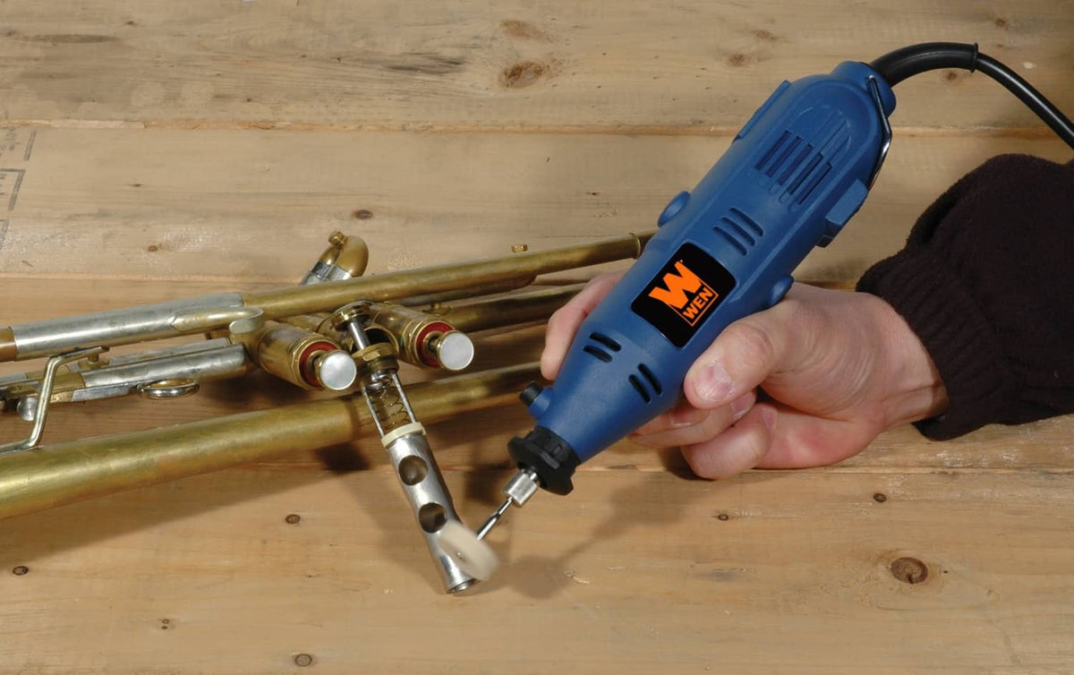 Handheld rotary tool with flex shaft finishing metal tubing on wooden board