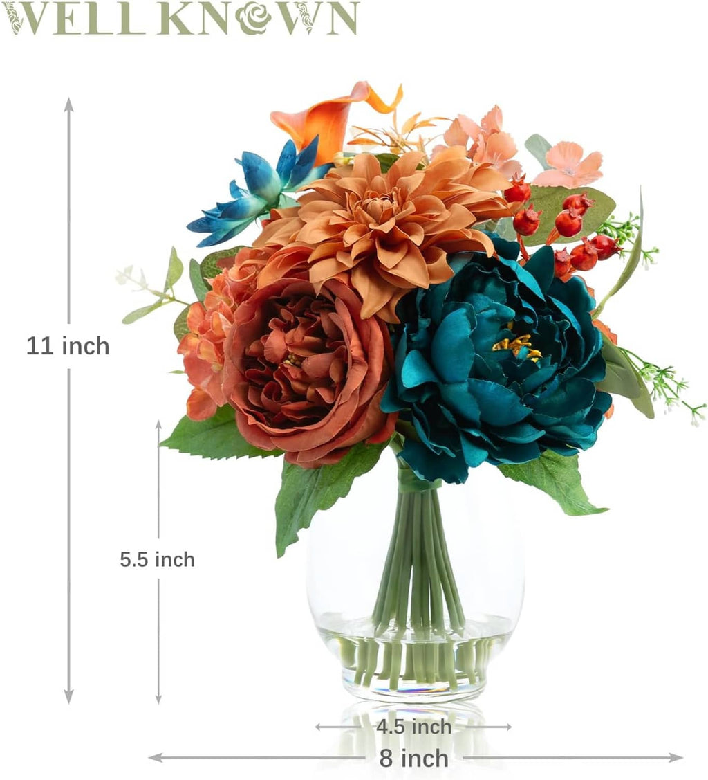 Clear glass vase with teal and orange artificial peony-dahlia bouquet and greenery