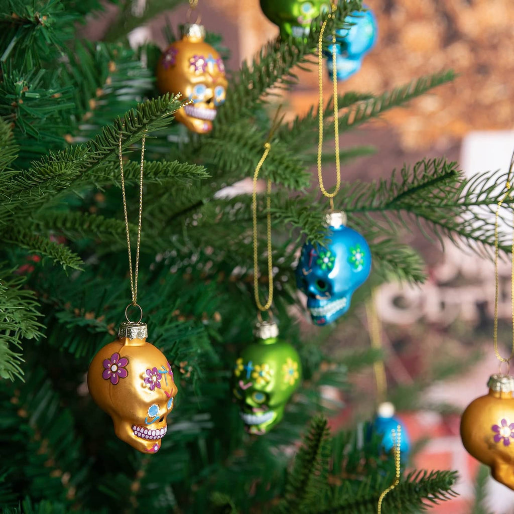 Day of the Dead glass skull ornaments hanging on a Christmas tree branch