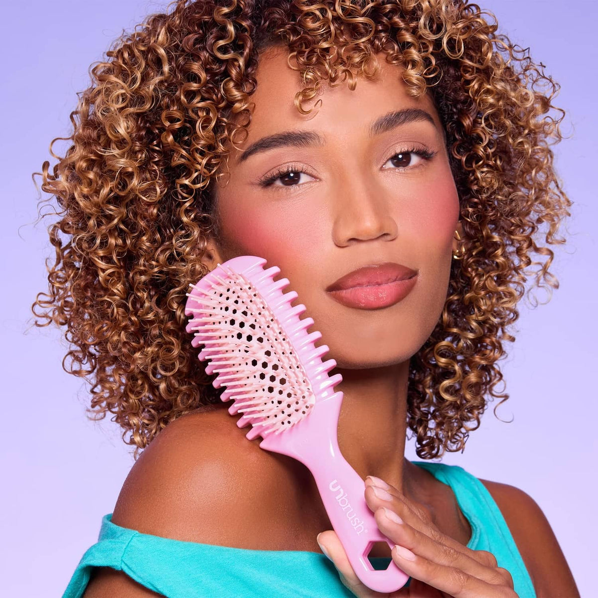 Pink curl brush with white-tipped bristle pad held near hair