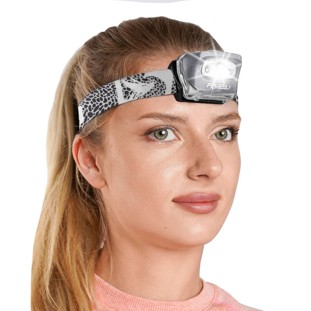 Foxelli LED headlamp on a person’s head with spotted fabric strap and bright front light