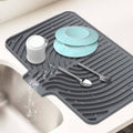 Gray dish drying mat with ribbed channels and built-in drain for plates and utensils