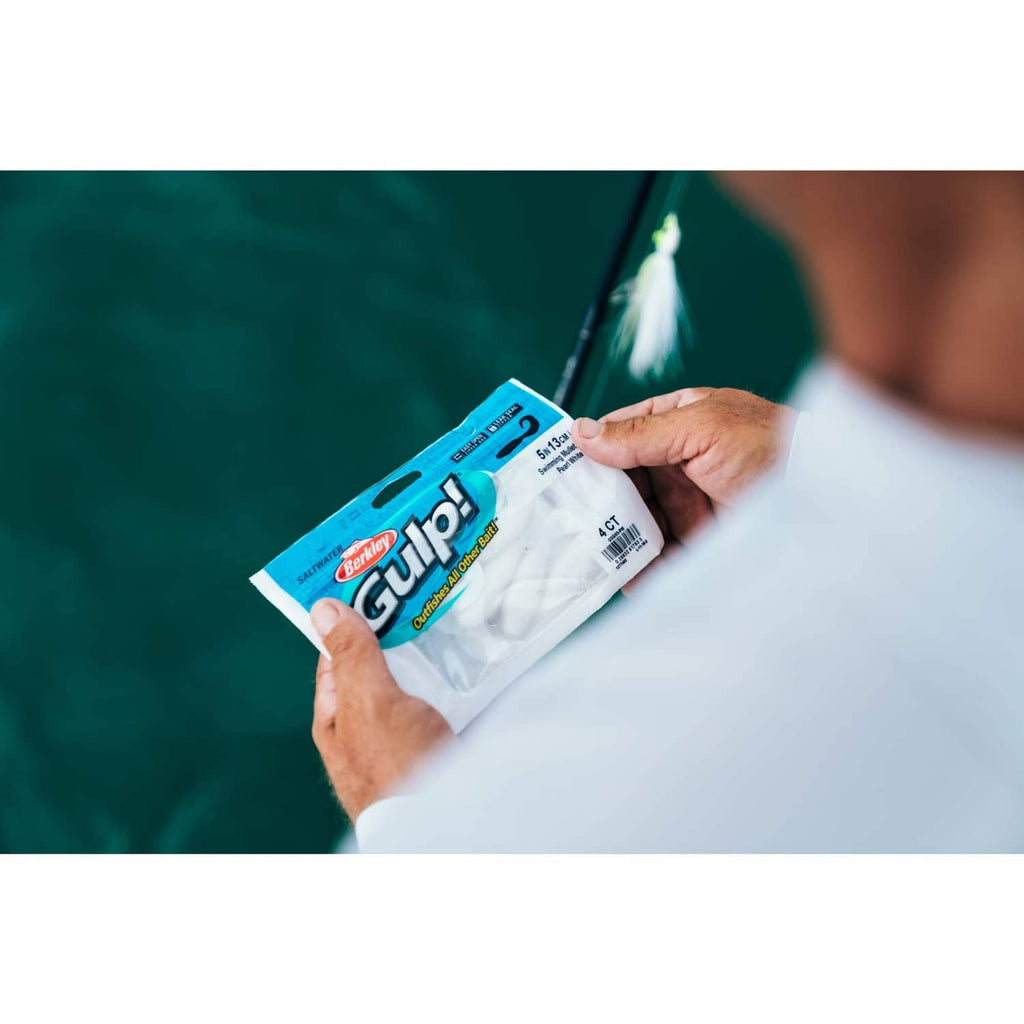 Hand holding Berkley Gulp! soft bait bag outdoors near water