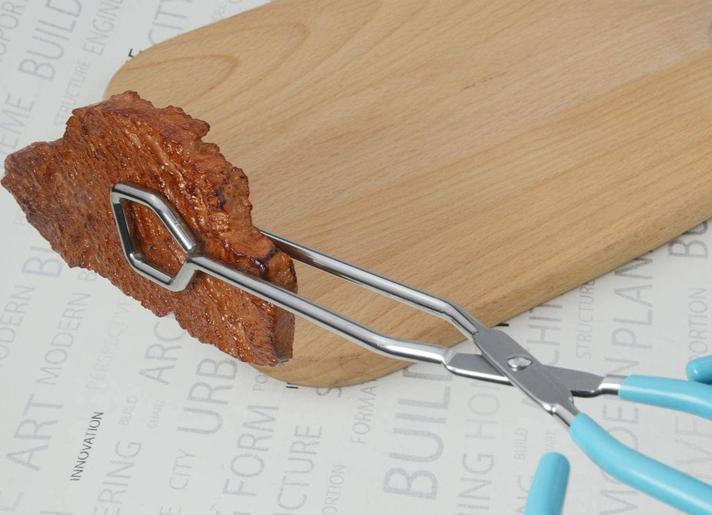 Stainless scissor tongs gripping meat on a wooden cutting board
