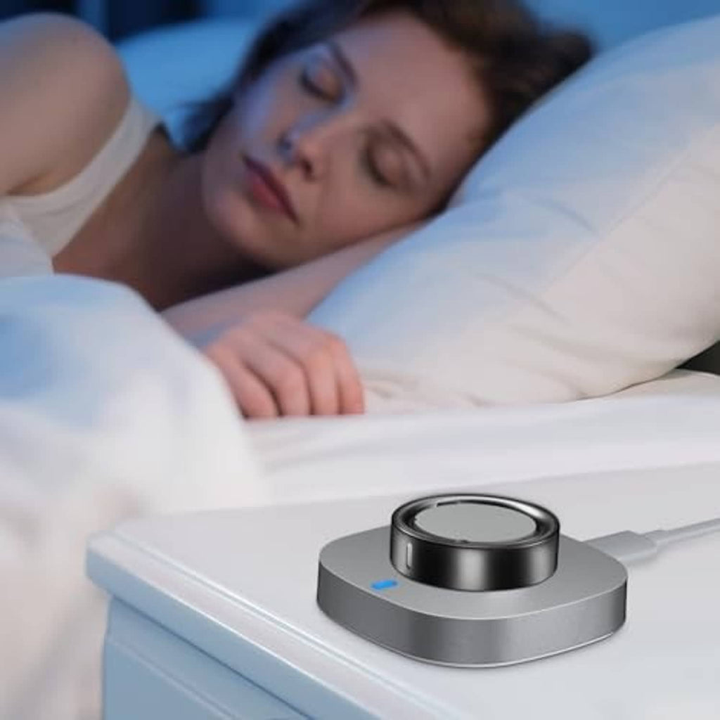 Ring charging dock on a bedside table near a person, dark silver base with blue indicator