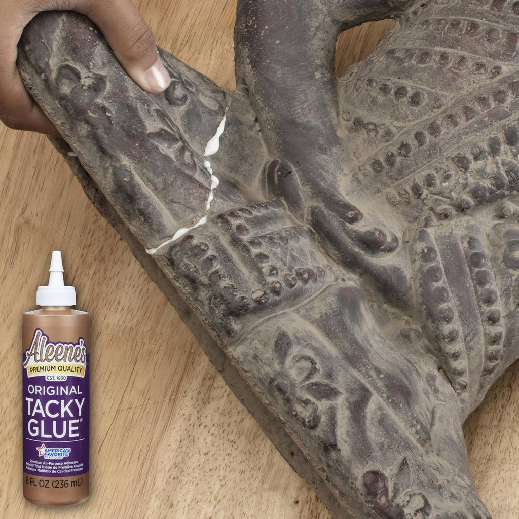 Aleene's Original Tacky Glue bottle with nozzle beside bonded craft material