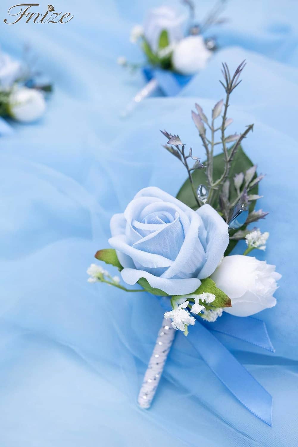 Single blue rose boutonniere with white blooms, green sprigs, and blue ribbon