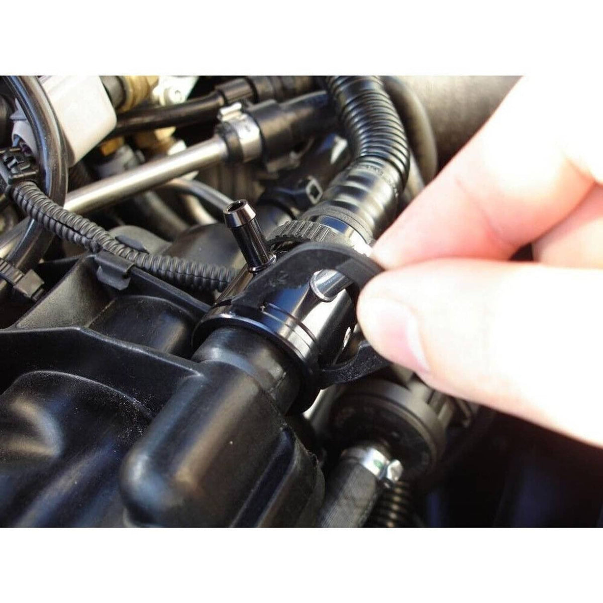 Black turbo vacuum tap sensor adapter installed near engine hoses, with three ports