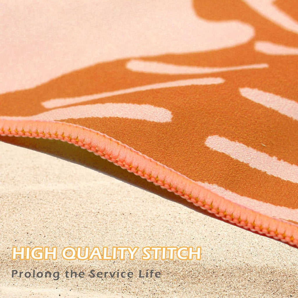 Orange beach towel with white palm leaf print, close-up of stitched border edge.