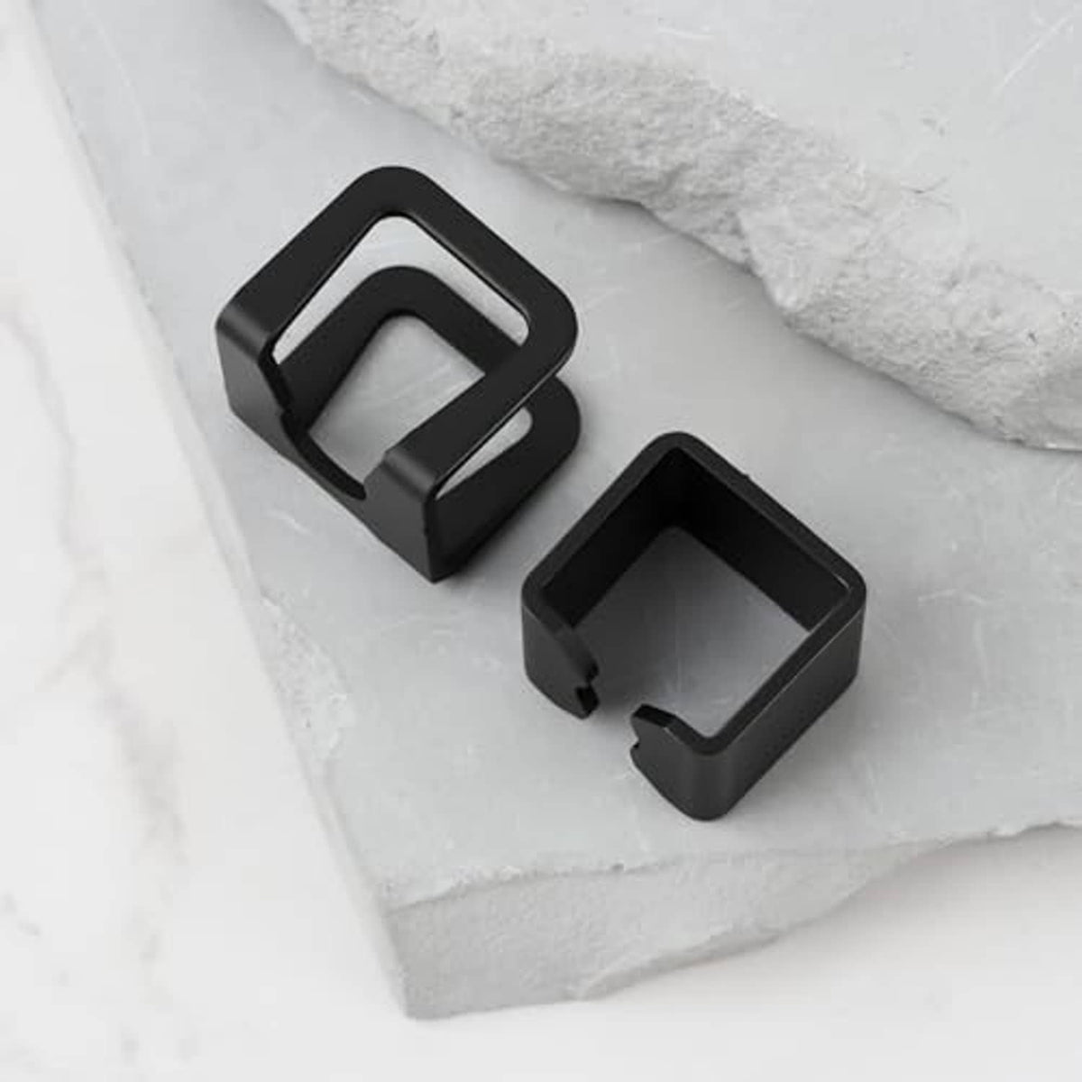 Two black jack spare part brackets with open square notch, side-by-side on tray.