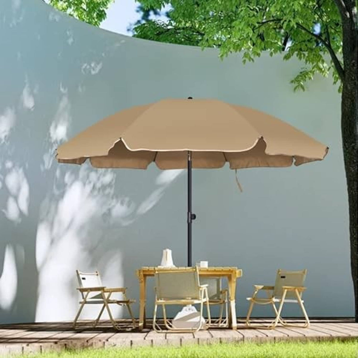 Tan patio umbrella open with black pole in outdoor yard beside seating set