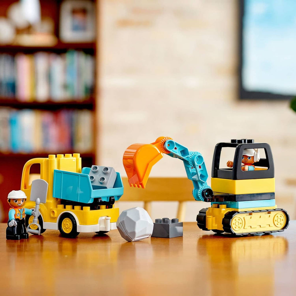 Yellow and blue construction truck and tracked excavator with worker figures and gray blocks