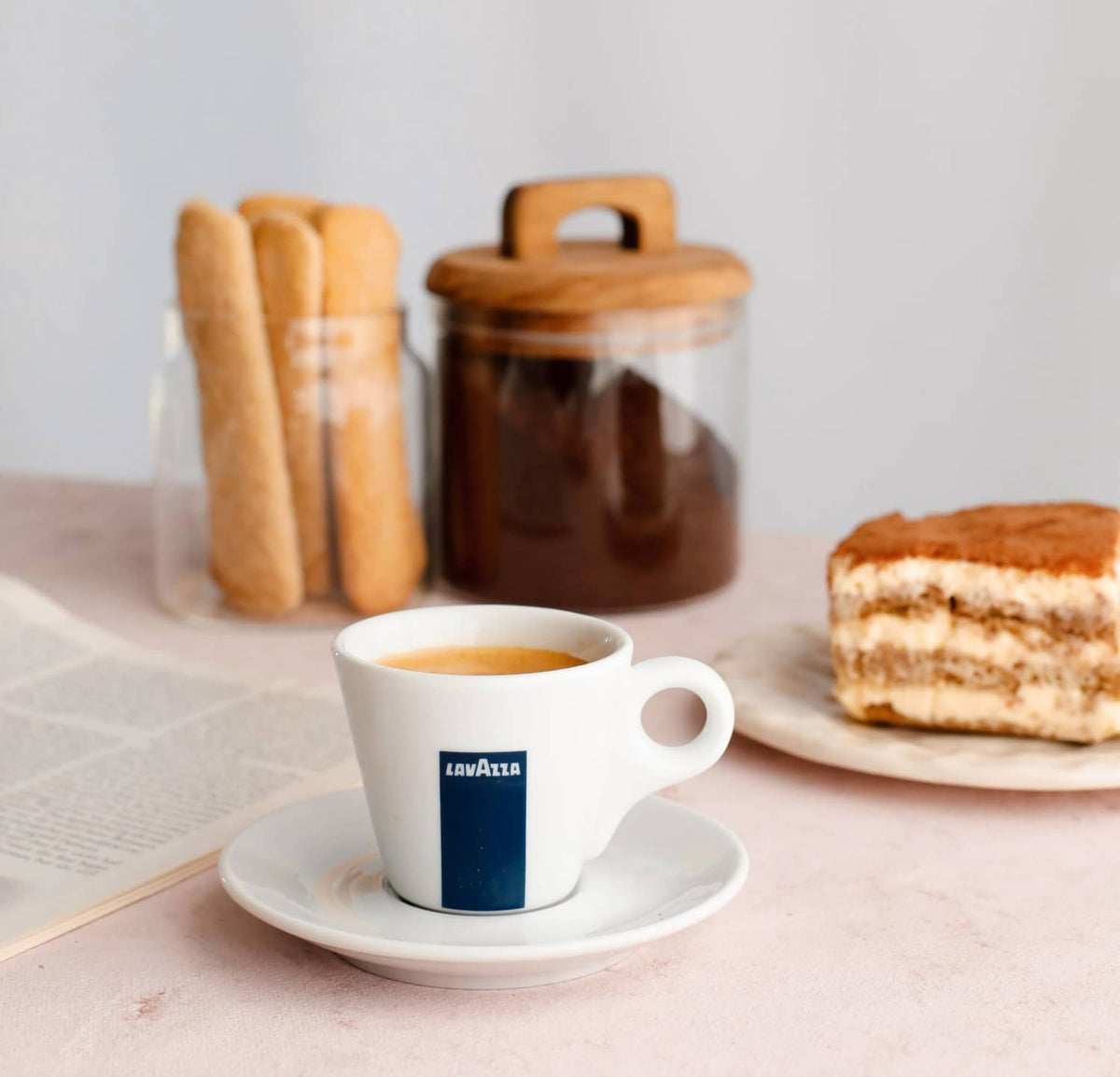 Lavazza espresso cup with crema on white saucer and pastries nearby