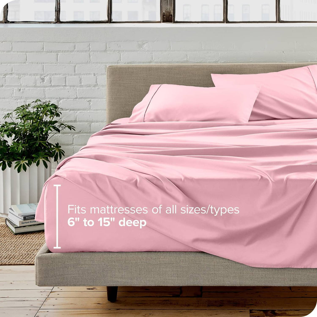 Light pink bed sheet set on a upholstered bed with two pillowcases and flat sheet