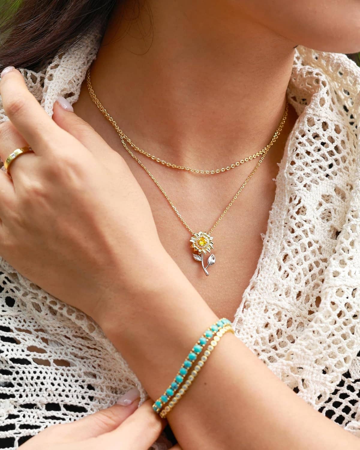 Gold-tone chain necklace with small sunflower spinner charm at collarbone