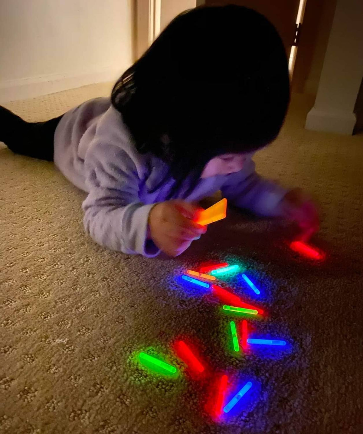 Mini glow sticks being held by a child, glowing blue, red, green, and orange
