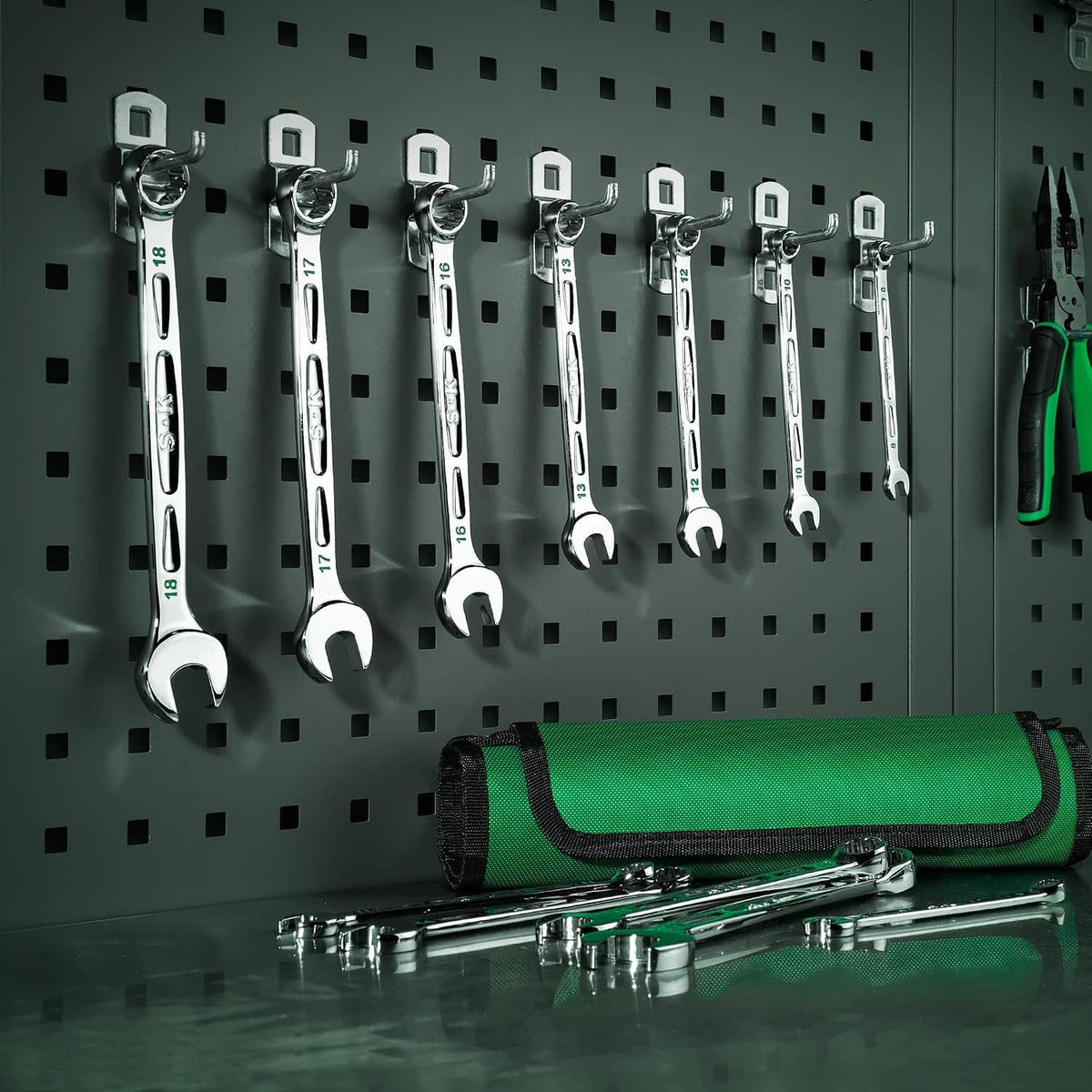 12-piece combination wrench set hanging on pegboard with green roll pouch