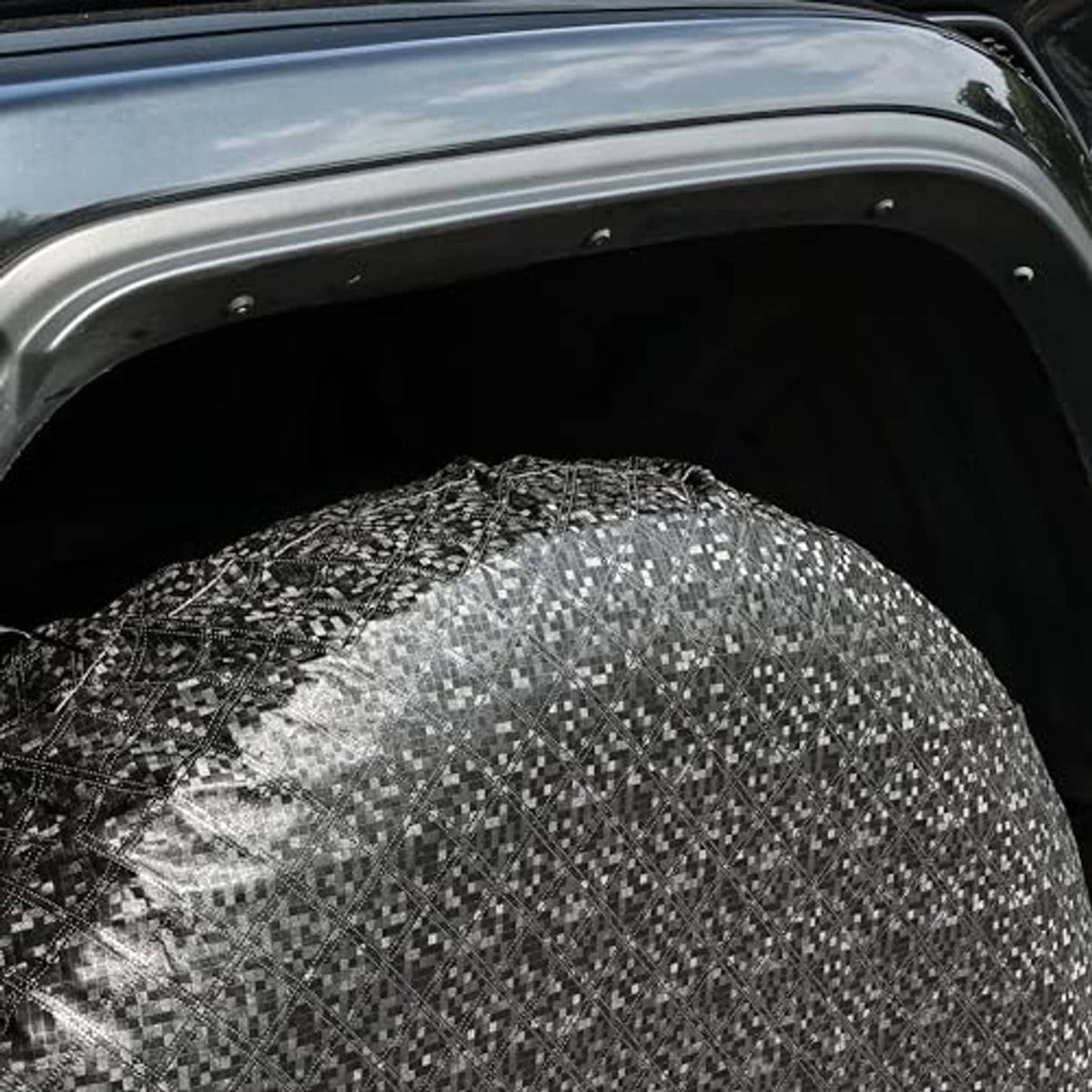 Close-up of a black RV wheel tire cover with patterned fabric near the wheel opening