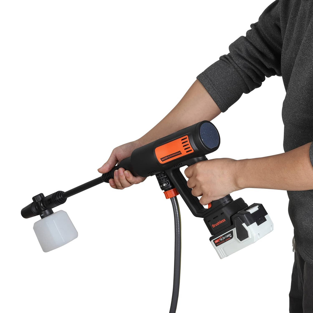 Cordless pressure washer with soap cup attachment held by a user’s hand