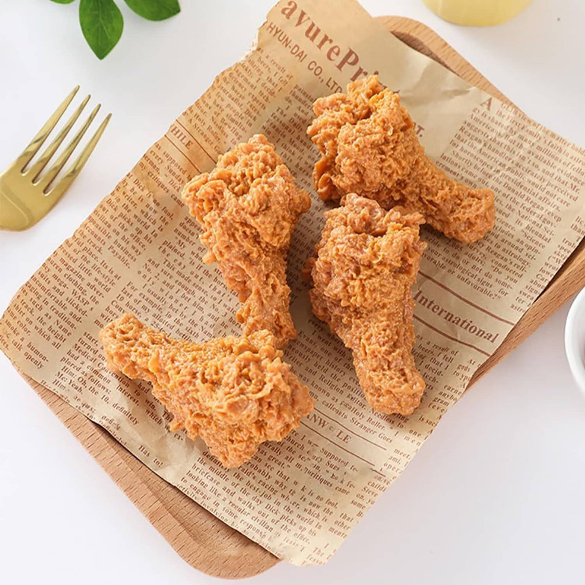 Faux fried chicken drumstick set on paper with fork, orange-brown textured legs.