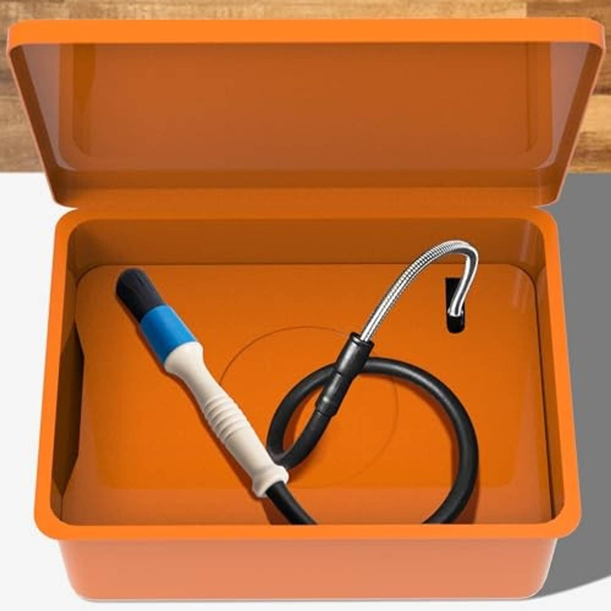 Parts washer brush and black hose set inside an orange storage case