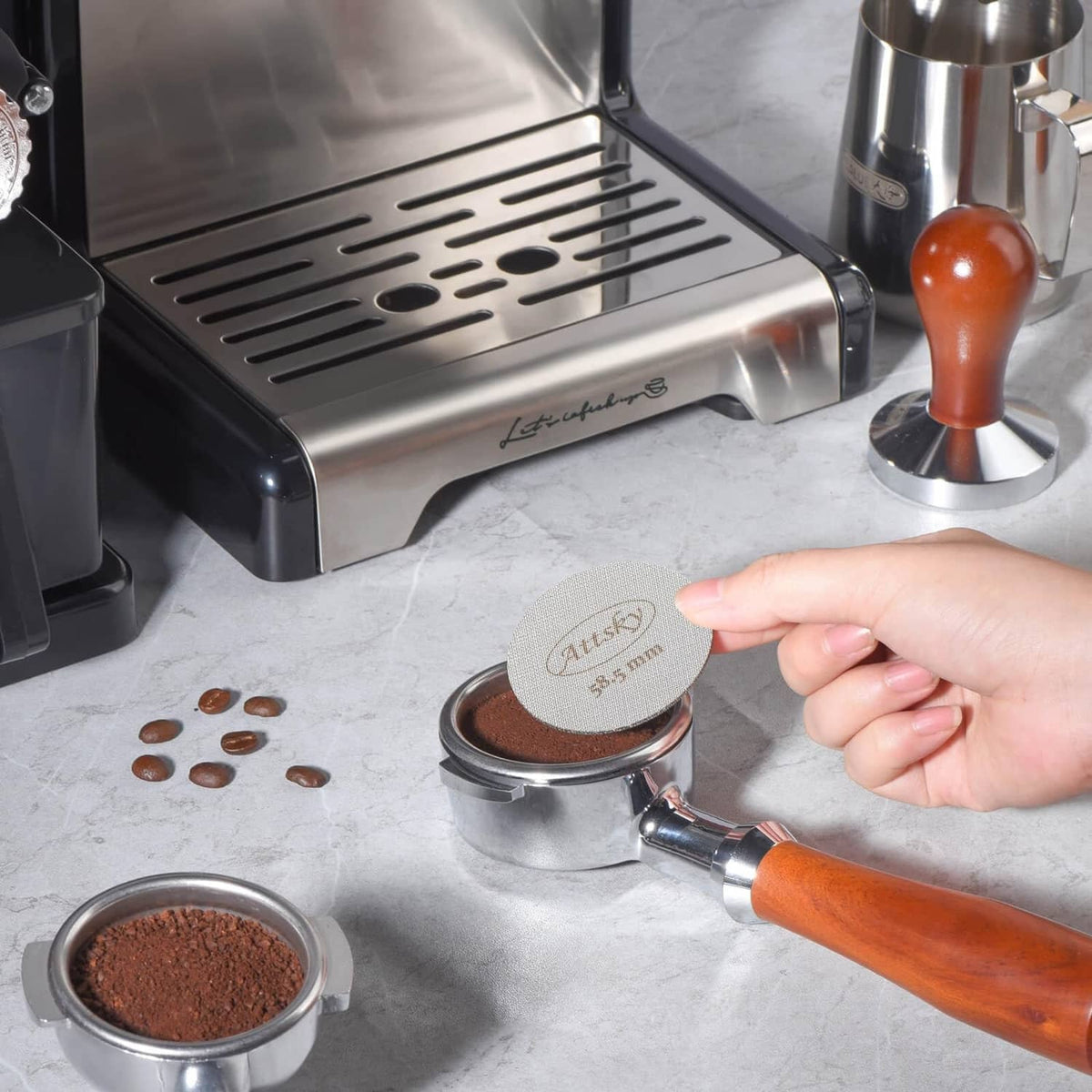Stainless espresso puck screen in hand on a portafilter basket, fine mesh top