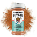 Dan-O's Outlaw Sweet Caribbean seasoning bottle with brown spice powder splash behind