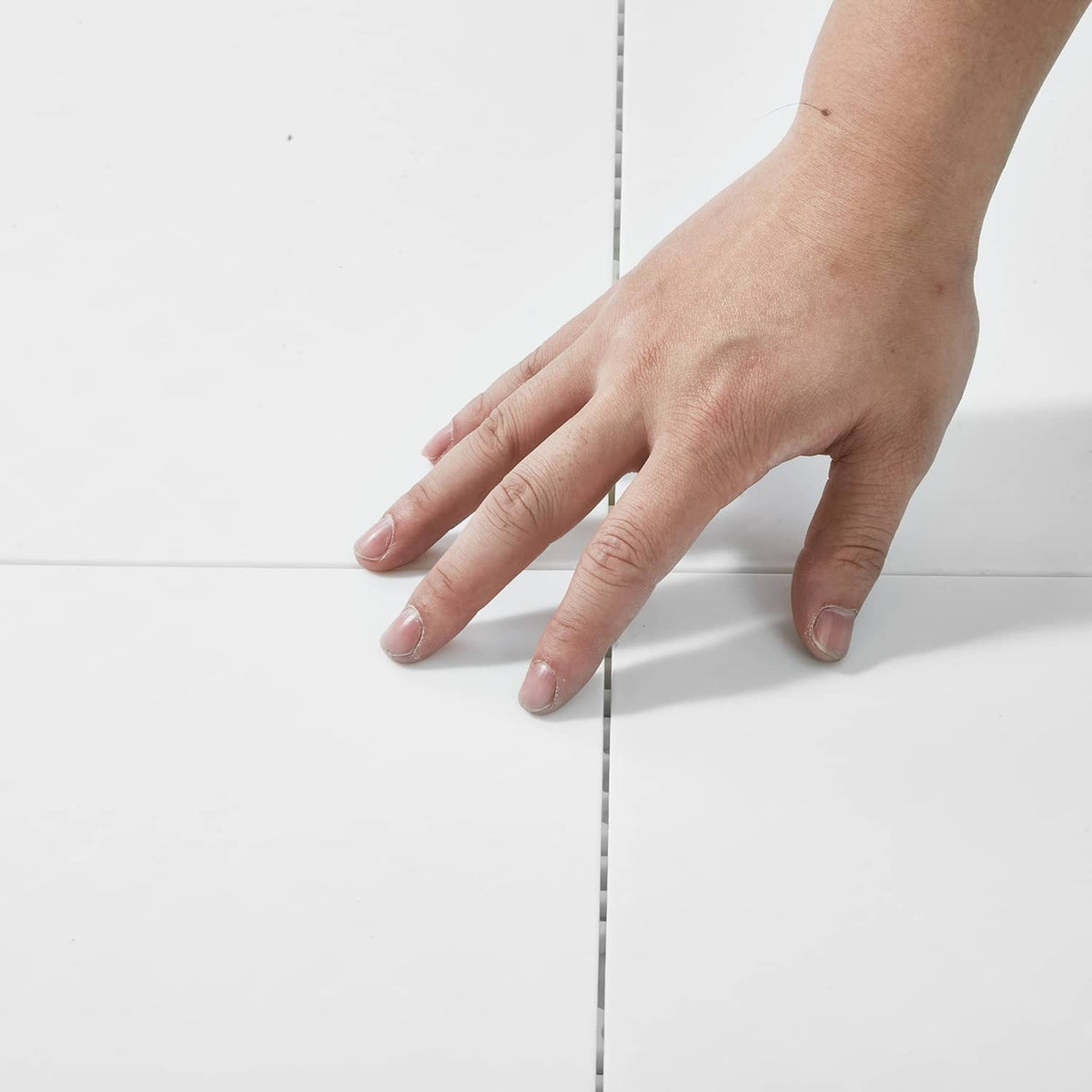 Interlocking exercise mat tiles, light color, snap-together seam under hand