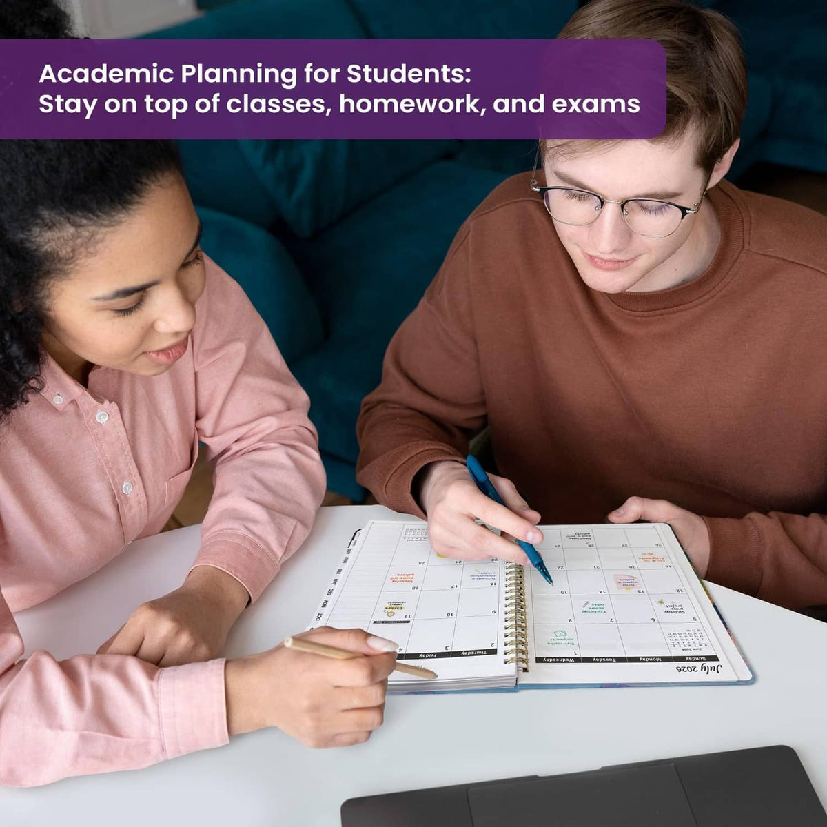People writing in an academic planner on a desk; colorful 2026–2027 pages visible
