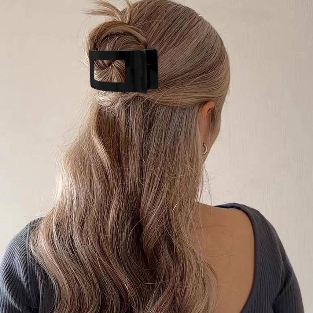 Bright black flat rectangular hair clip close-up on a high bun, secured in hair