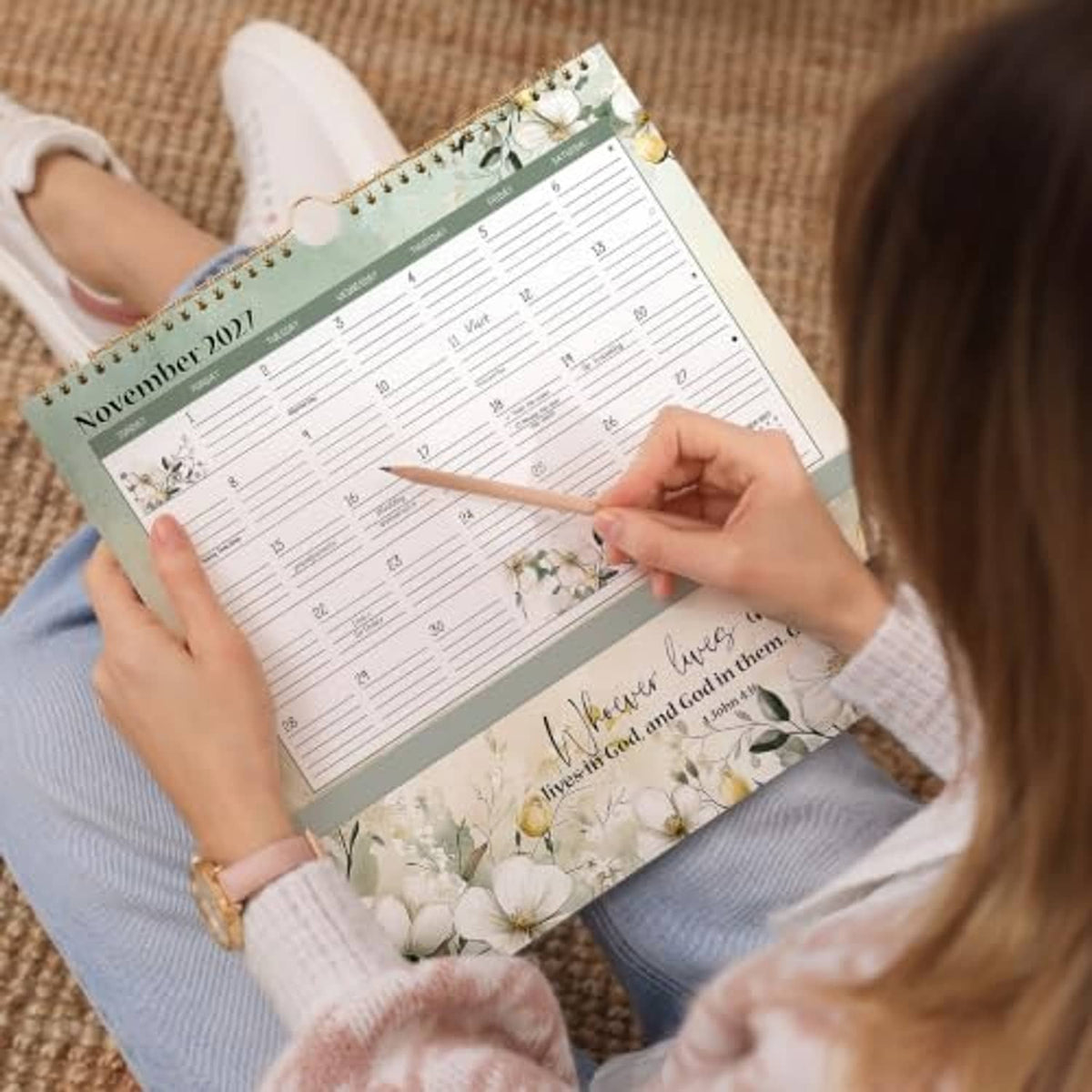 2027 wall calendar in hands, showing November grid and floral pocket cover
