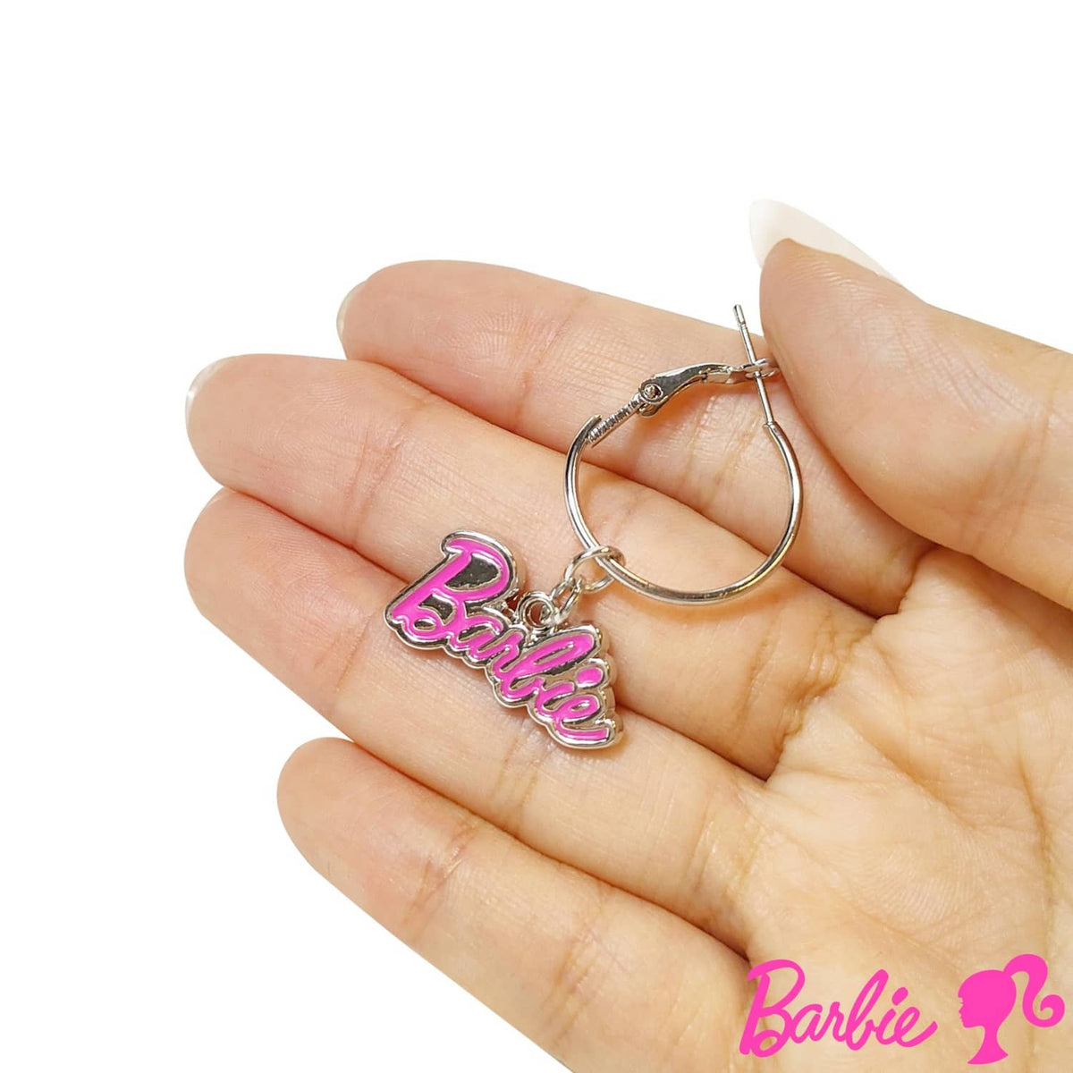 Hot pink Barbie charm hoop earring on silver tone, shown held in a hand