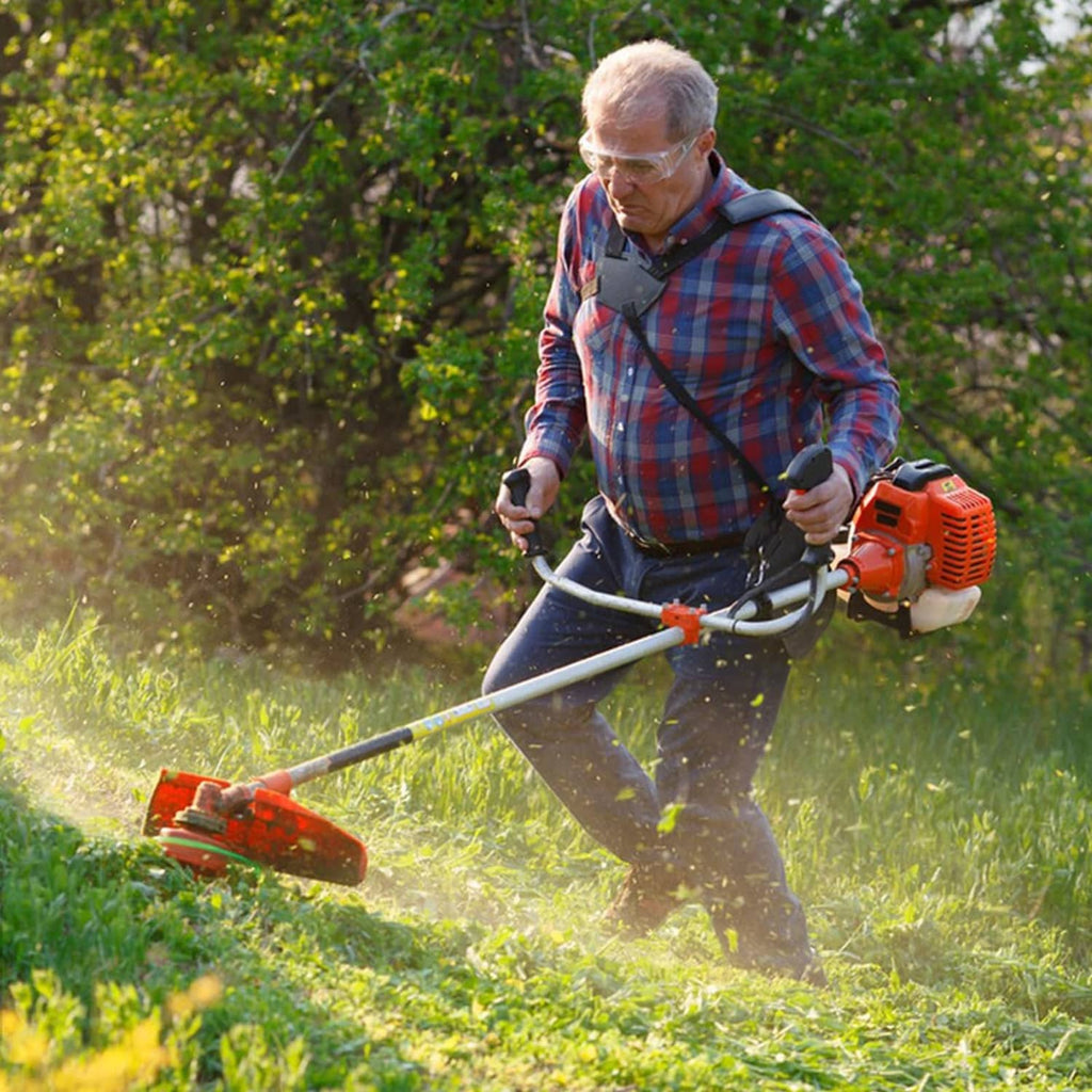Gas string trimmer in use with cutting head over overgrown grass