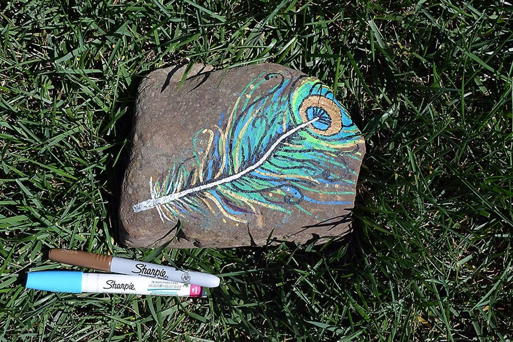 White Sharpie oil-based paint marker drawing on dark stone surface, medium point