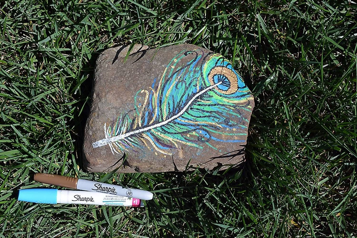 White Sharpie oil-based paint marker drawing on dark stone surface, medium point