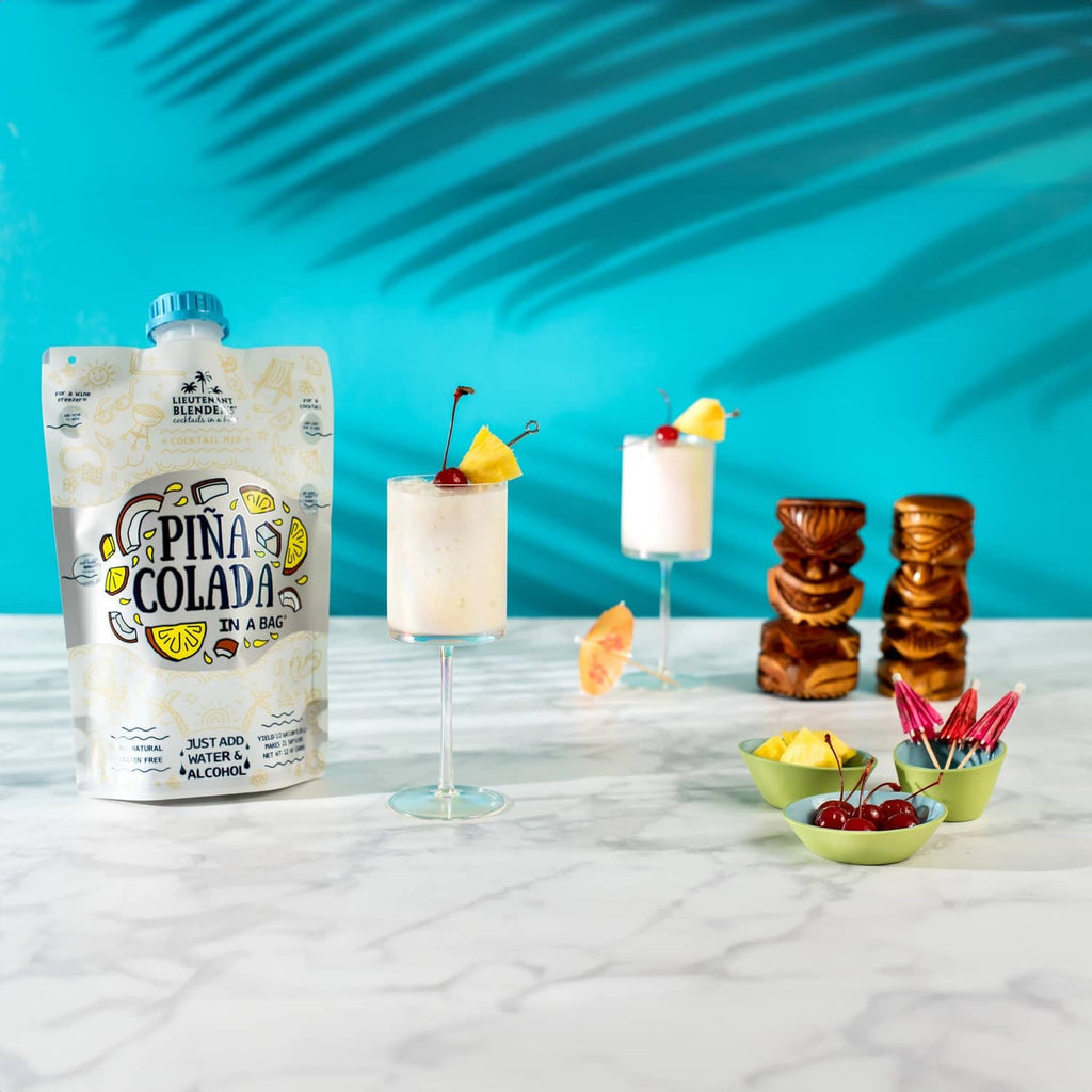 Pina colada cocktail mix pouch with two cocktails, cherries, and tiki-style cups