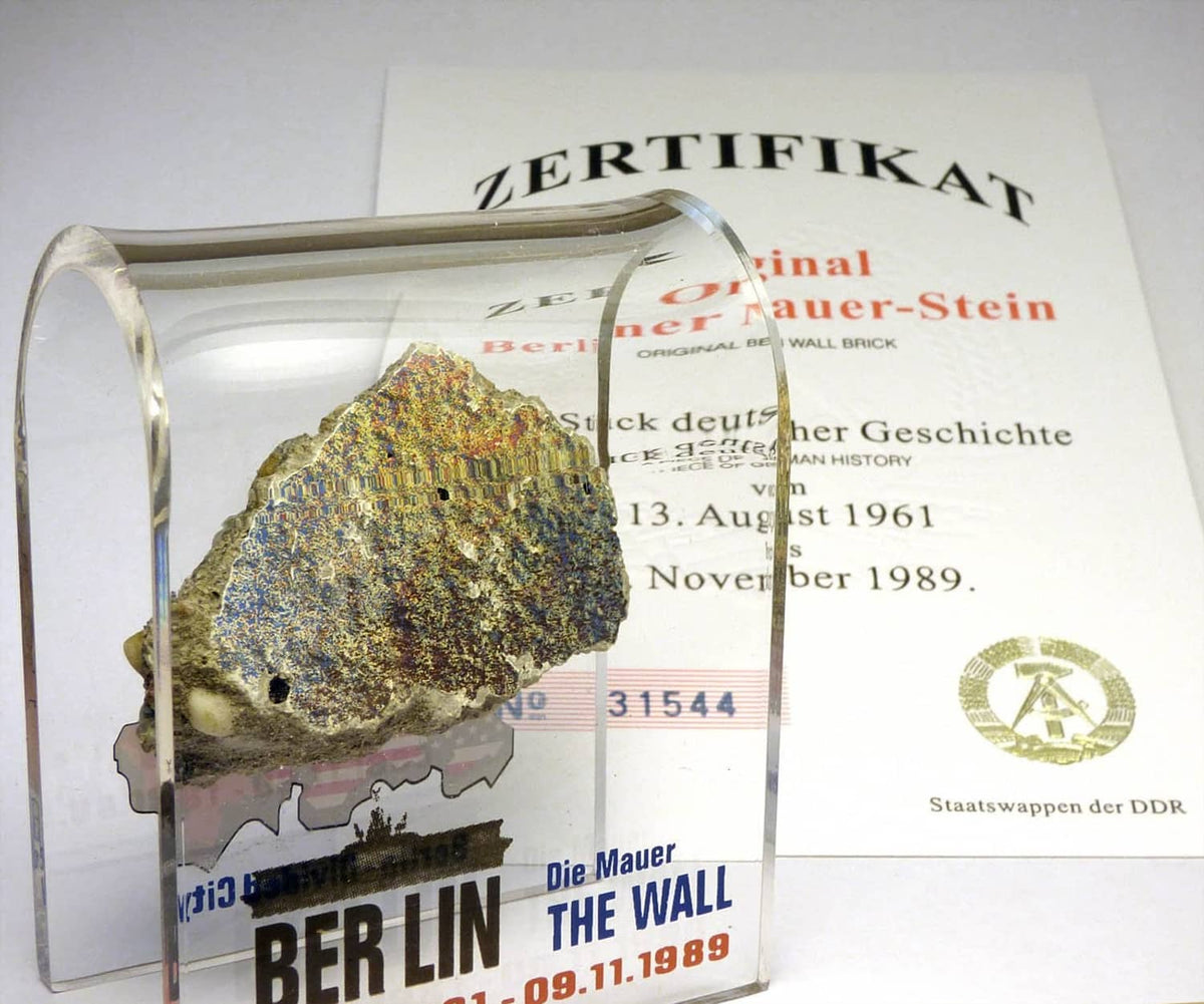 Acrylic display case with rough rock specimen and ZERTIFIKAT card, certificate side visible