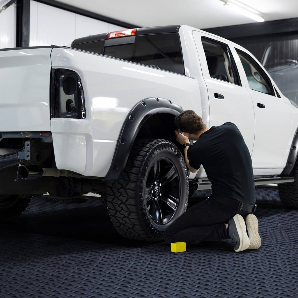 Dark gray interlocking garage floor tiles with textured diamond pattern under a truck