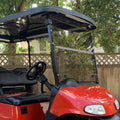 Tinted golf cart foldable windshield on red EZGO RXV, scratch-resistant panel