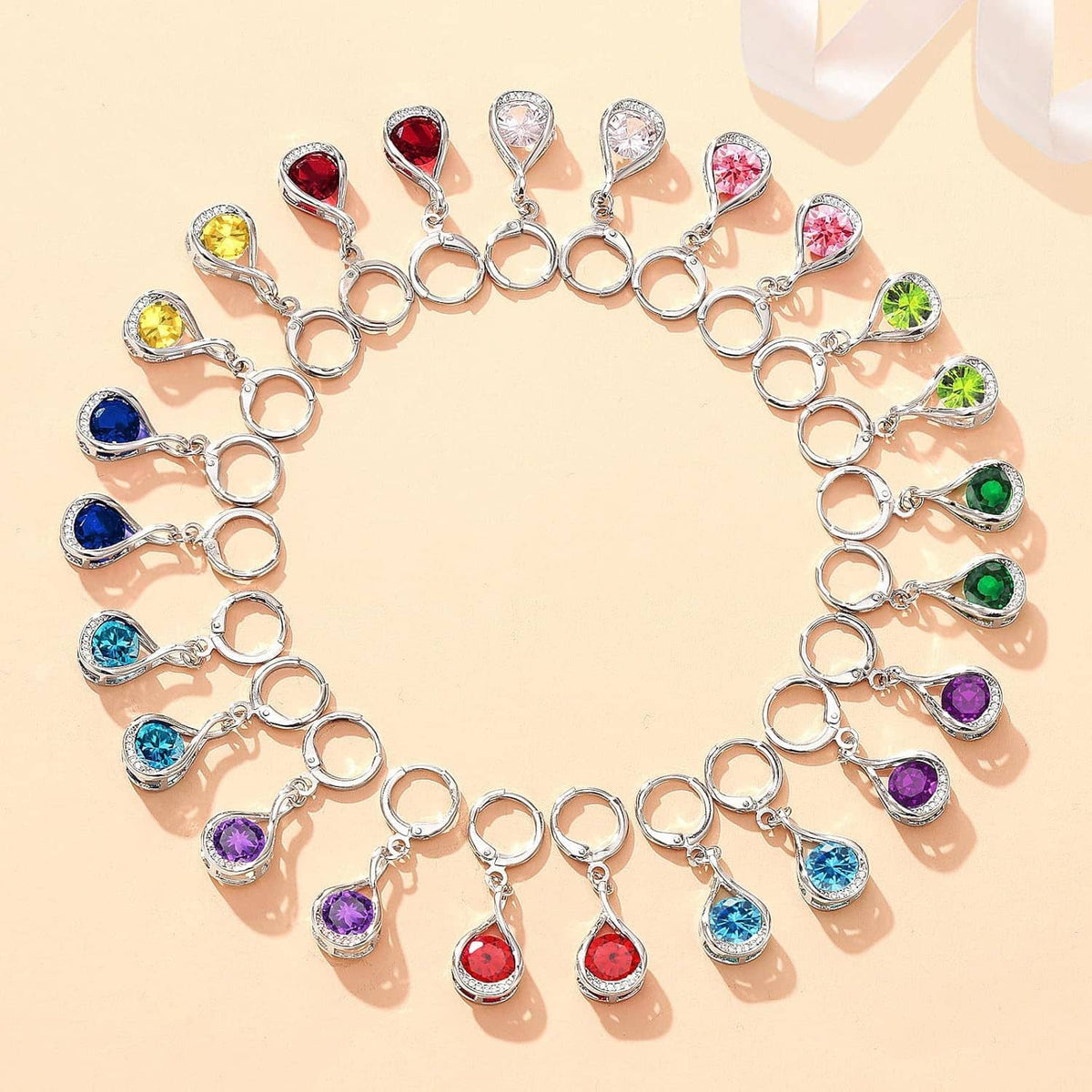 Silver necklace set displayed in a heart shape with colorful teardrop gemstone charms