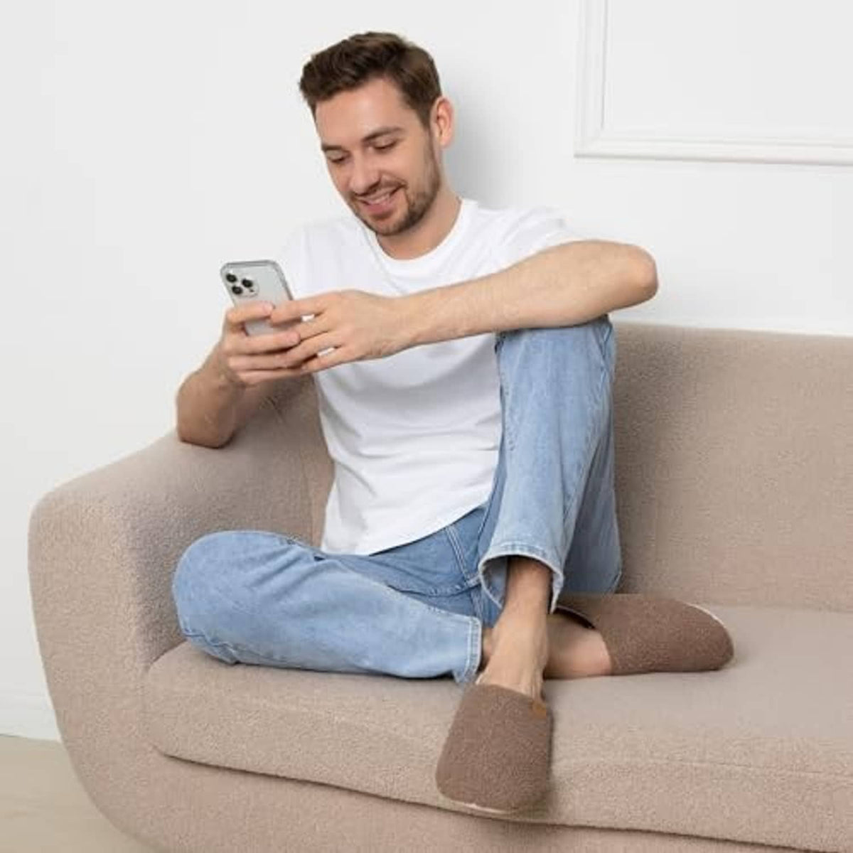 Brown plush men’s slippers with white-edged collar worn on a couch