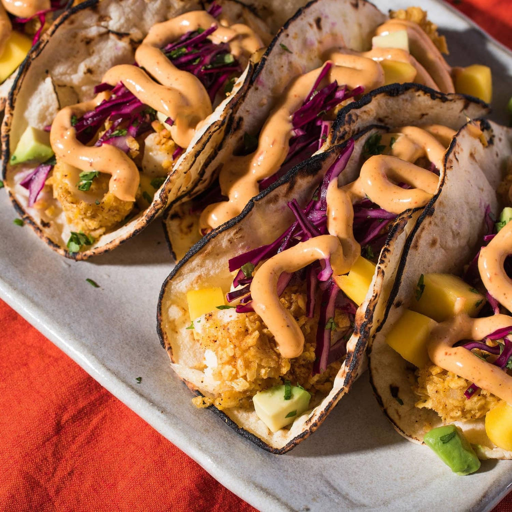 Two tacos with seasoned beef, shredded cabbage, and creamy sauce drizzle