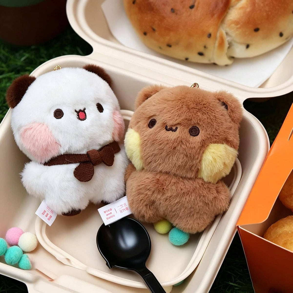 Plush bear keychains in a tray: white bear and tan bear with brown bow ties