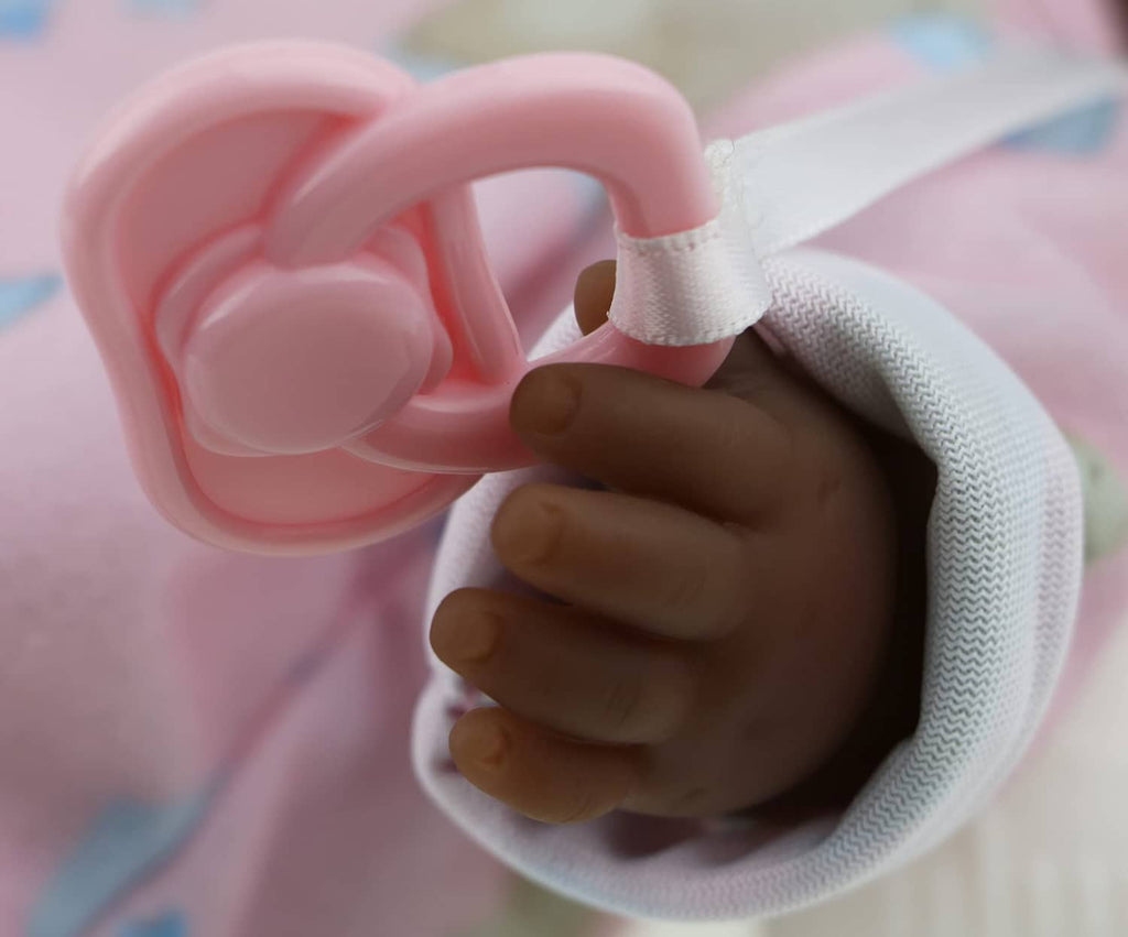 Close-up of a pink baby doll hand holding a pink pacifier