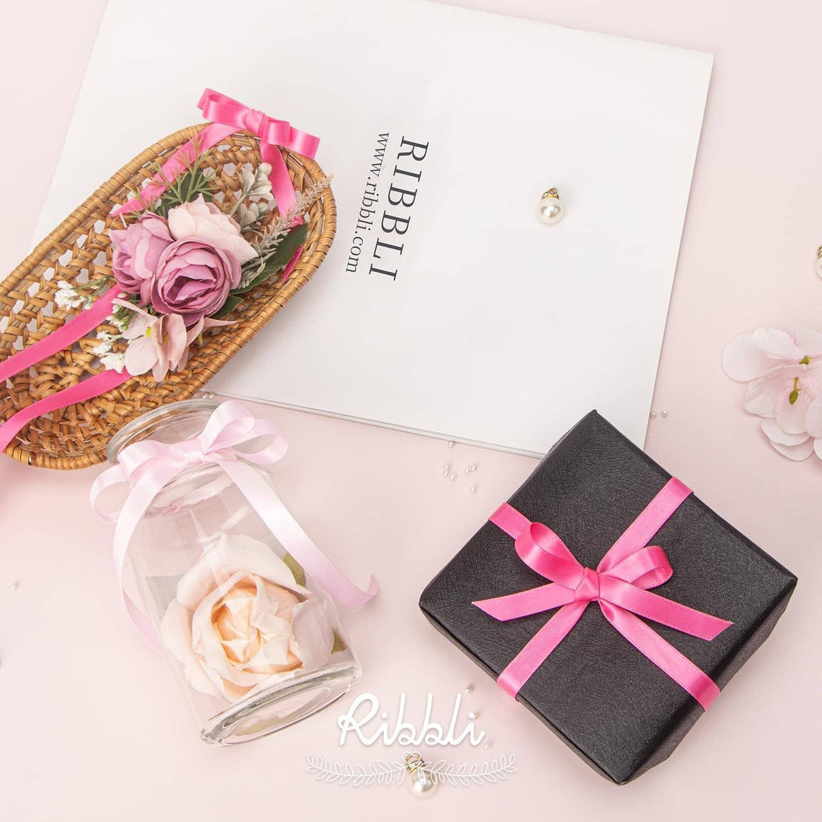 Pink satin ribbon tied in gift bow with decorative flower basket and wrapped box