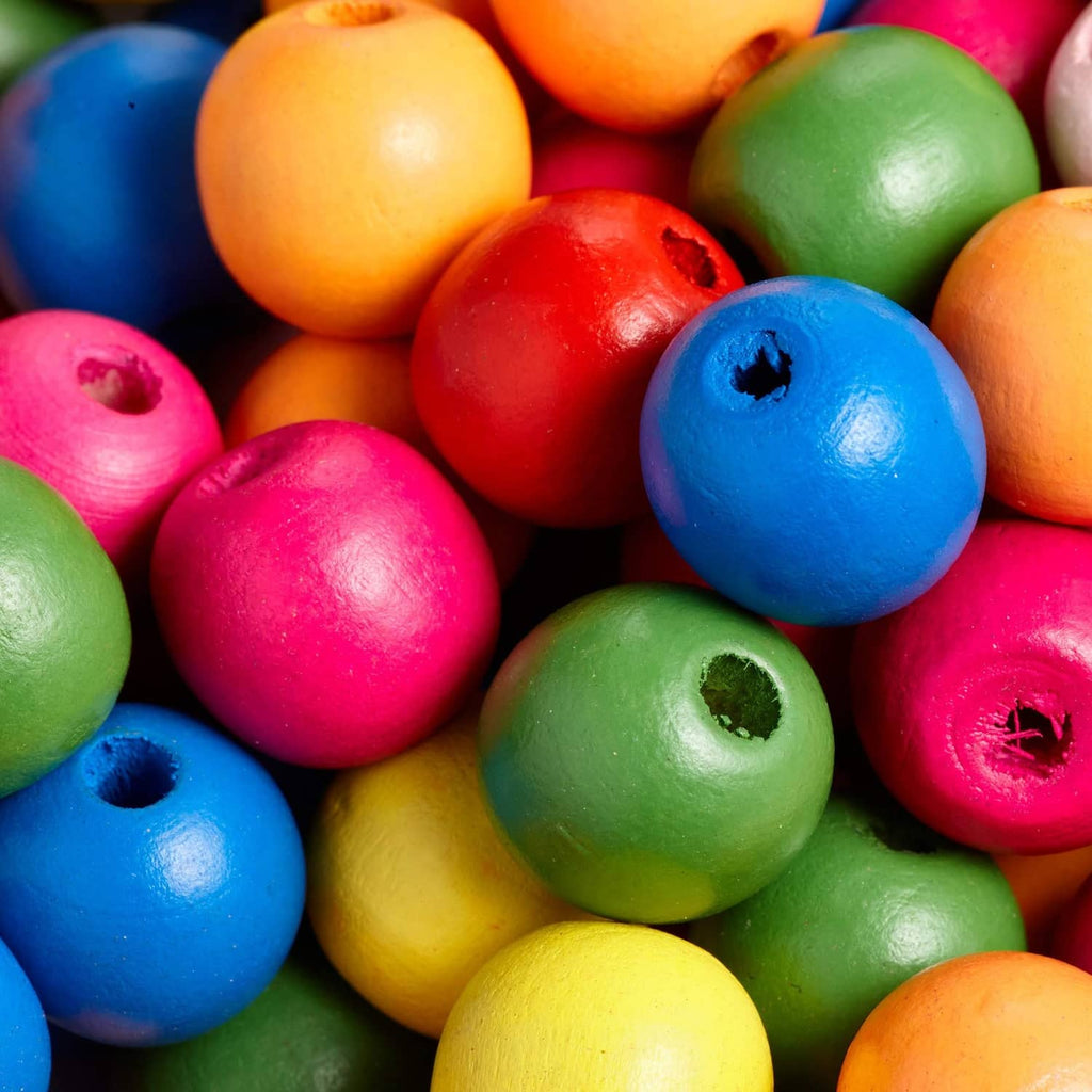 Close-up of round multicolor wooden beads with center holes in blue, pink, green, yellow, red