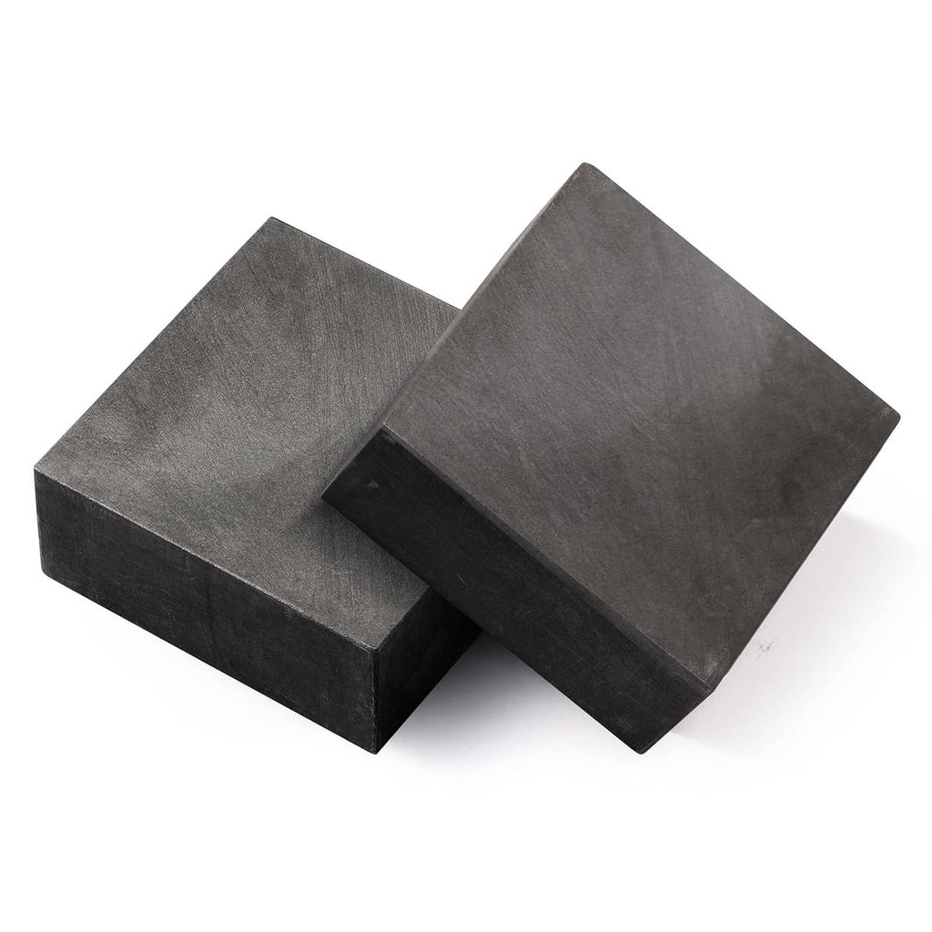 Graphite ingot blocks, dark gray rectangular prisms stacked and overlapping