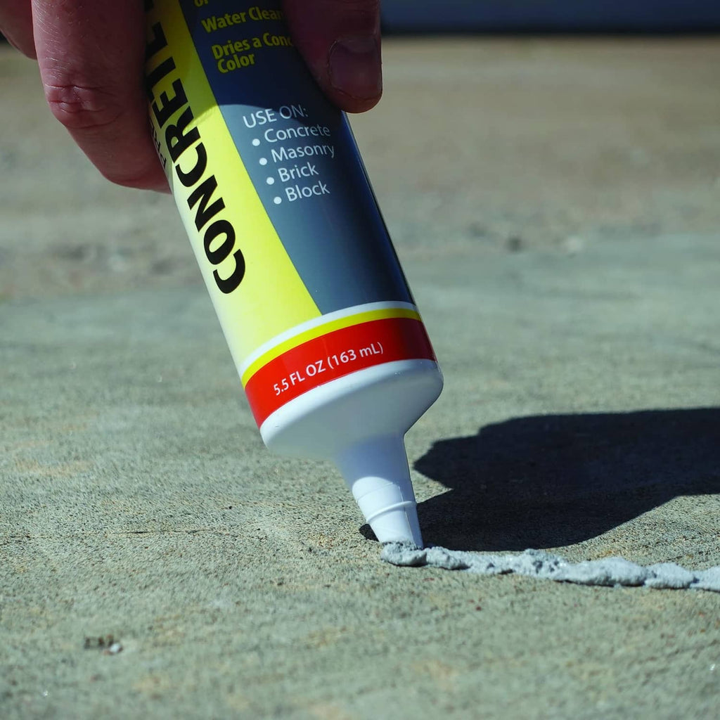 Concrete patch tube dispensing gray cement filler on a concrete surface